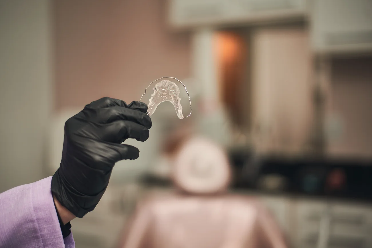 Alinhador transparente segurado com luva na clínica.